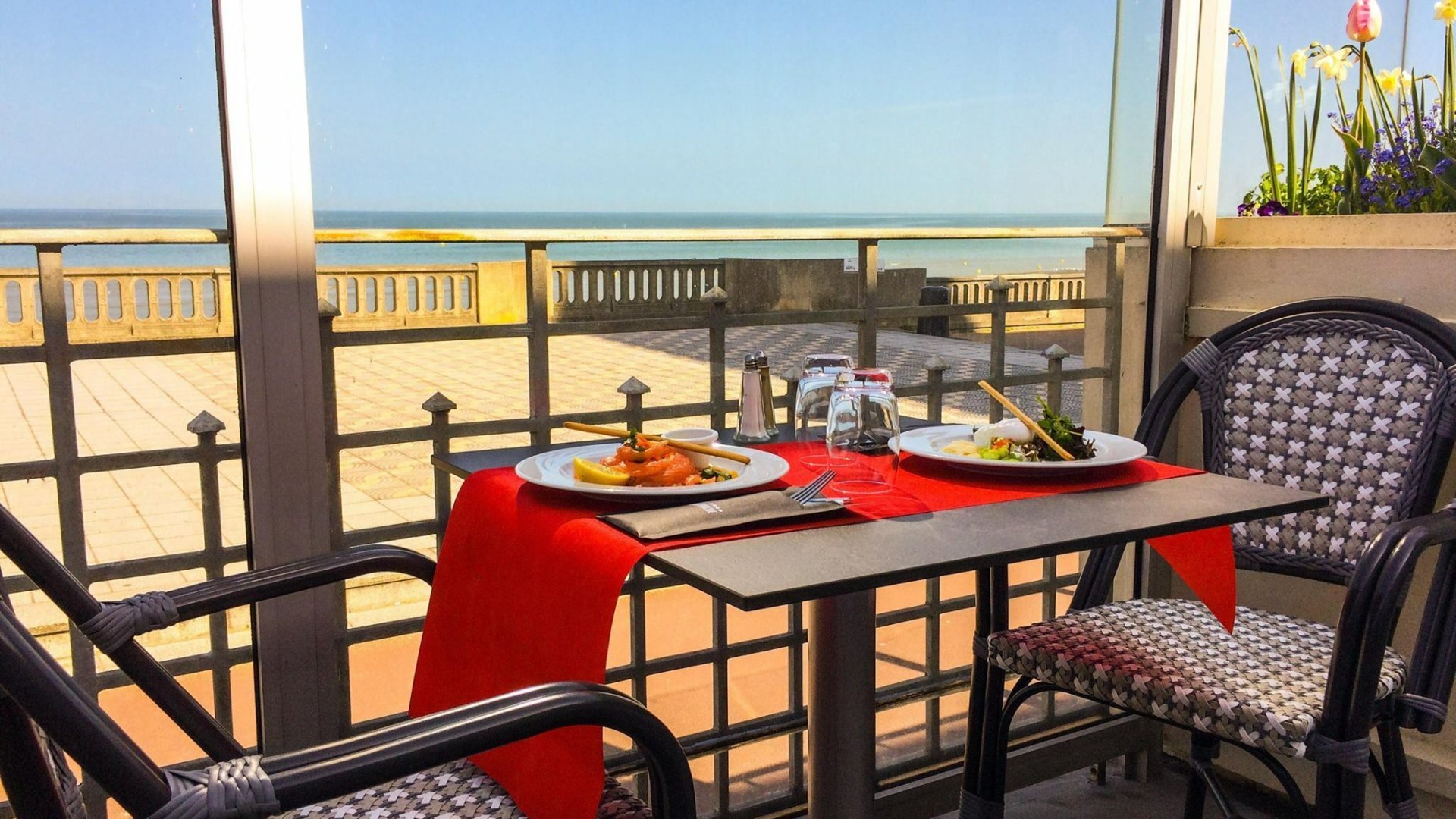Table en terrasse du casino de Cabourg avec vue panoramique sur la mer, idéale pour un moment de détente ou un repas convivial.